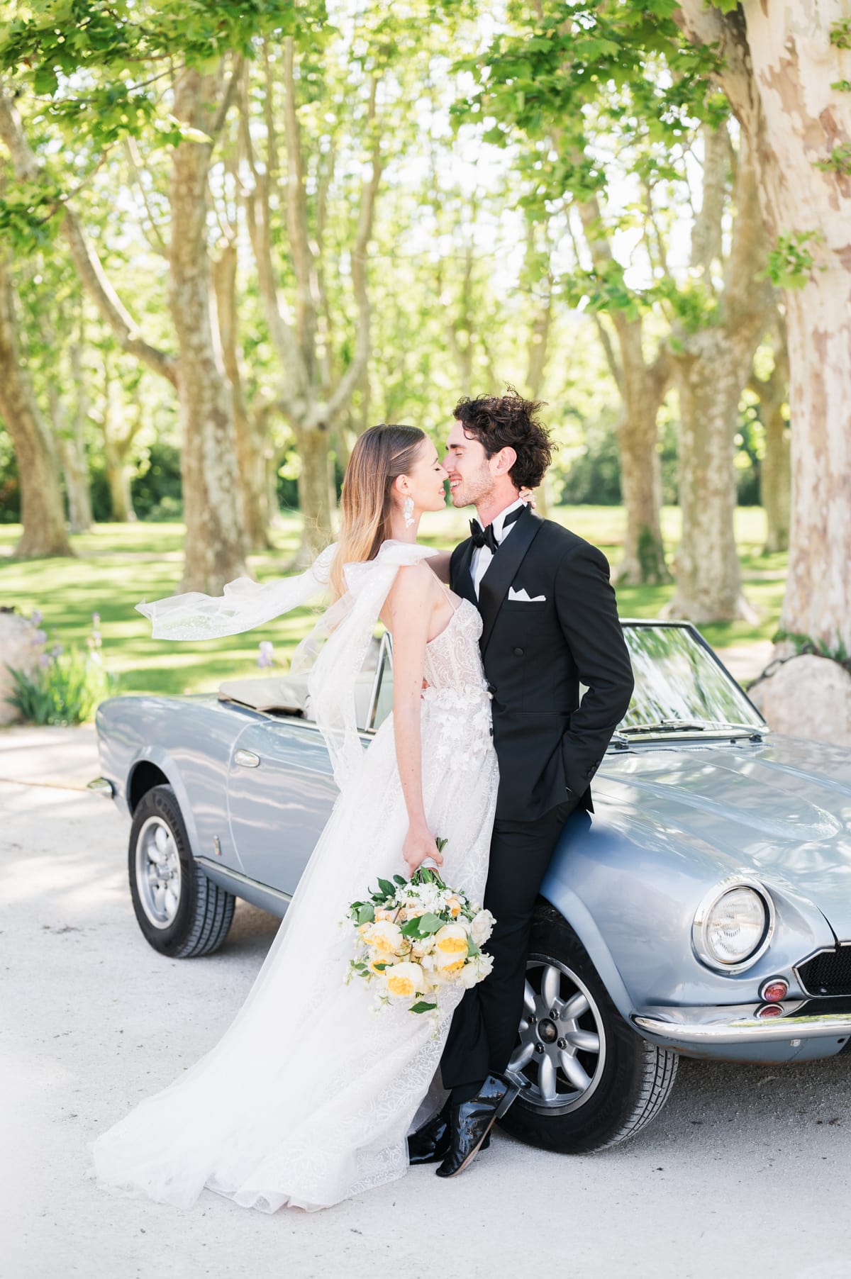 Couple de mariés devant une voiture de collection